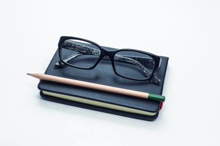 Pencil and black frame glasses on the notebook, Isolated on white. Business concept.の写真素材