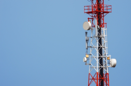 Telecommunications tower, painted white and red in a day of clear blue sky.の写真素材