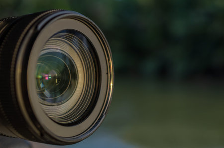 Camera lens. The backdrop is a natural green background.