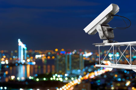CCTV security on the building. Below is a view of the city lights at night, focus blur.