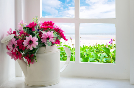 Bouquet of artificial flowers in a window to look through the window at the sea. relaxation conceptの写真素材