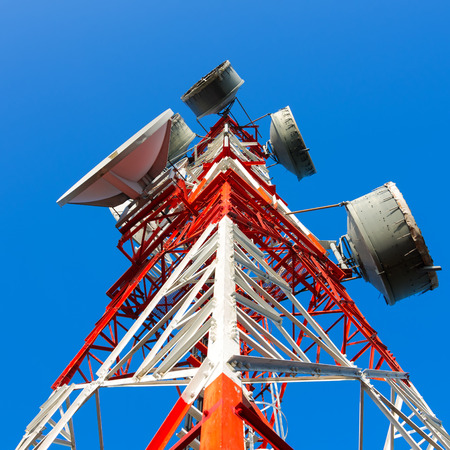 Telecommunications tower, painted white and red in a day of clear blue sky.の写真素材