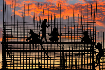 Silhouettes of laborers Buildings and structures were built. Stunning sunset sky.の写真素材