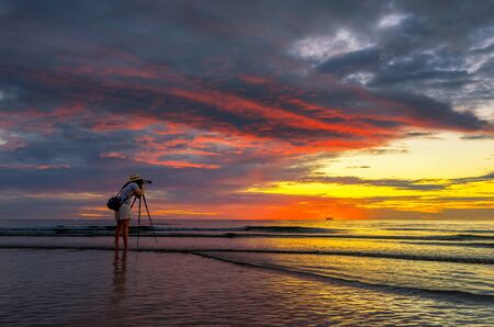 Woman photographer shooting sunrise at Cha Am Beach. Phetchaburi, Thailand.の写真素材