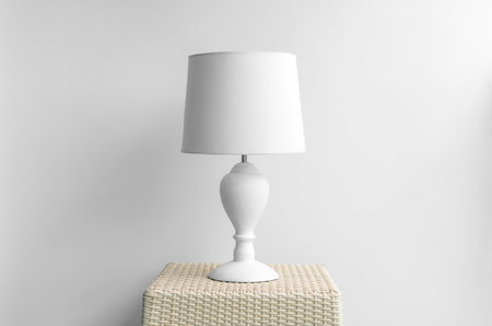 Lamp on a night table next to a bed.の写真素材