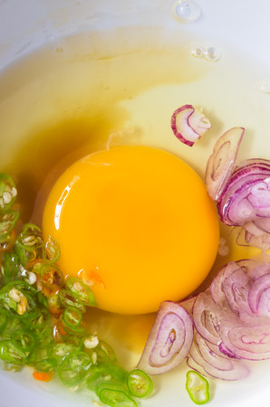 Raw egg yolk in the white bowl With chili and shallot fish sauce sliced and made an omelet.の写真素材