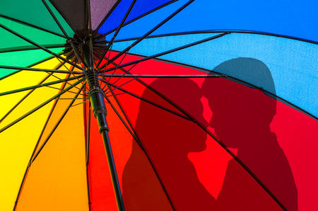 Couple silhouettes Rear multicolored umbrella On the bright sky.の写真素材