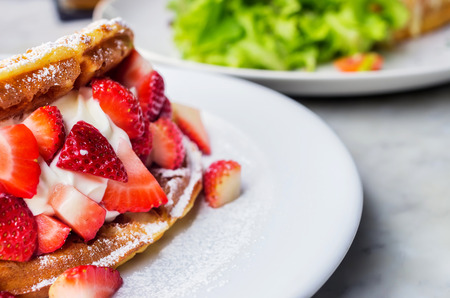 Waffles with strawberries with ice cream. Extra honey on white plate.の写真素材