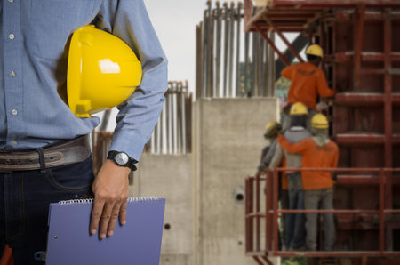 Engineer holding a yellow helmet for the safety of workers on a background of building new...