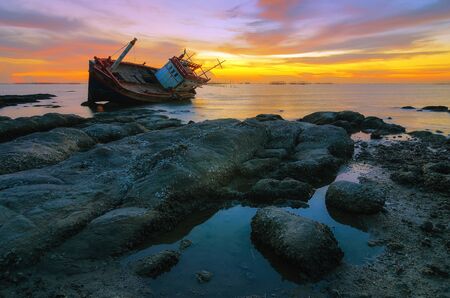 Dilapidated old fishing boat on the beach with dramatic sky.の写真素材