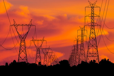 Silhouettes high voltage transmission towers on field の写真素材