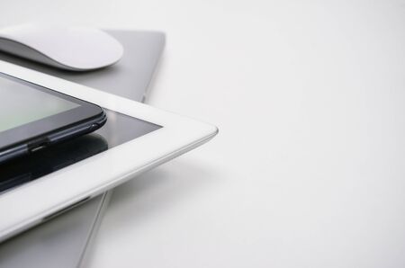 Phone, tablet pc, notebook and mouse on white desk.の写真素材