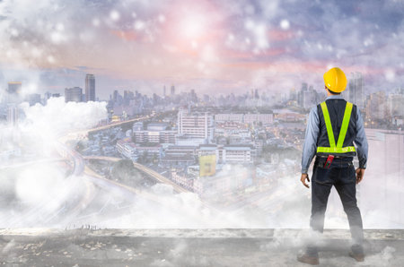 Double exposure of Engineer holding a yellow helmet for safety of the workers. A modern high-rise...