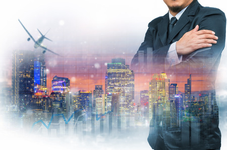 Double exposure of businessman with cityscape and financial graph on blurred building background.の写真素材