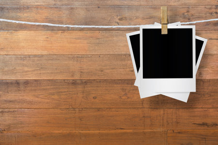 Blank photo frame with clothespin hanging on wooden background, with clipping path.