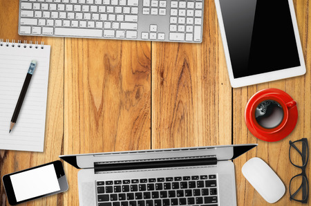 Office desk table with laptop, mouse, digital tablet, notepad, pencil and coffee cup, Top view with copy space.の写真素材