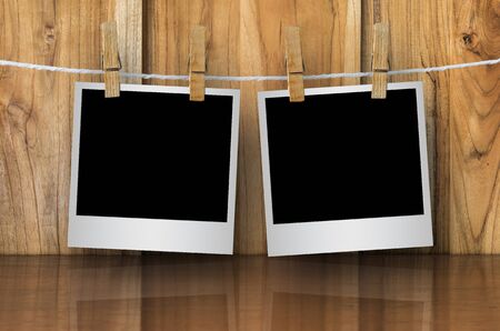 Clothespin hanging with blank photo papers on wooden backgroundの写真素材