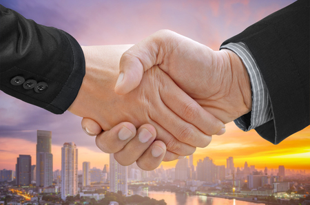 Double exposure of businessman handshake on blurred cityscape background.の写真素材