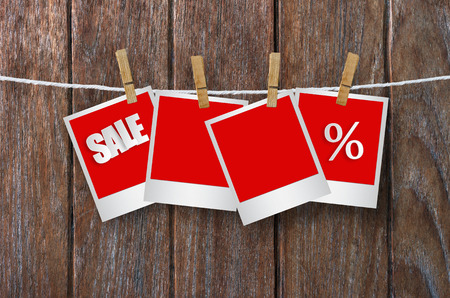 Sale paper label in photo frame paper hanging on wooden background, discount banner.の写真素材