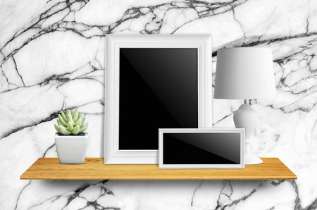 Empty picture frame isolated with clipping path, lamps and potted cactus on bookshelf  - For product display.の写真素材