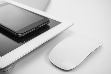 Phone, tablet pc, notebook and mouse on white desk.の写真素材