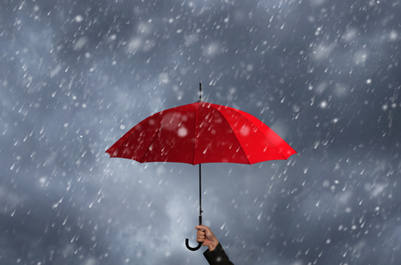 Red umbrella in the hands of businessmen amid a rainstorm.の写真素材