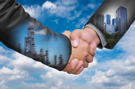 Double Exposure of a businessman handshake on the background blurred downtown and industrial. Concept of an agreement green energy.の写真素材