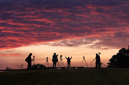 Silhouettes of many photographers. Beautiful sky and sunrise.の写真素材