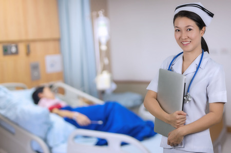 Asian nurse holding notebook with background blur patient room.の写真素材