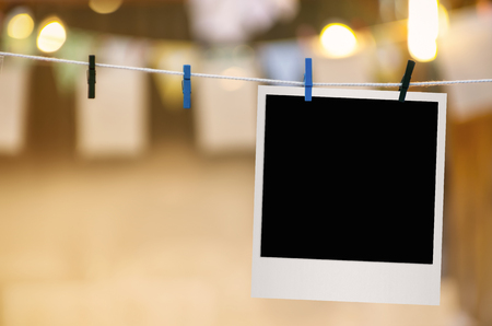 Blank photo frame with clothespin hanging on blurred light background.の写真素材