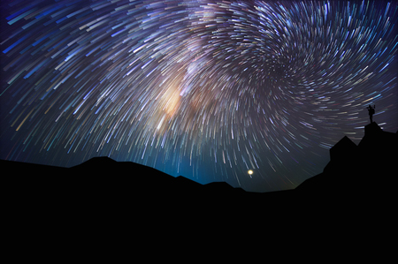 Silhouette of man with backpack on hill watching the stars at night, long exposure.の写真素材