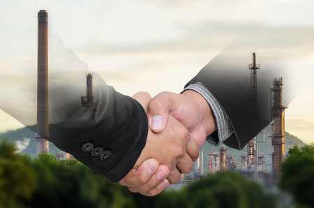 Double exposure of businessman handshake on blurred refinery plant background.の写真素材