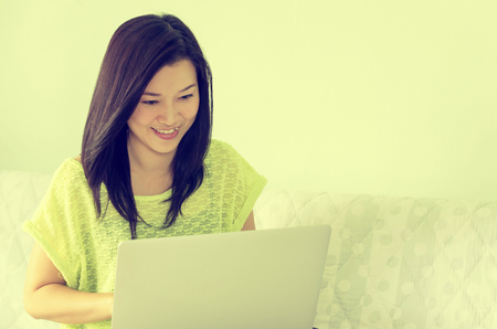 Happy young beautiful asian woman using laptop, Indoors. Vintage Style.の写真素材