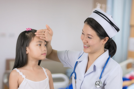 Asian nurse in uniform temperature measurements are girls with background blur patient room.の写真素材