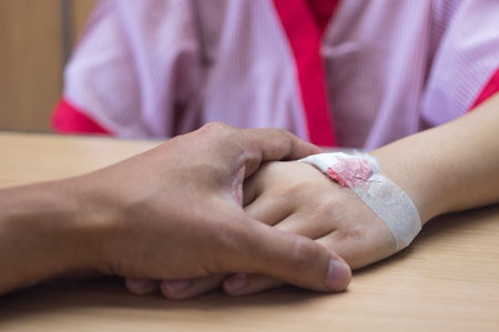 Holding patient hand with IV tube in hospital, showing care and love.