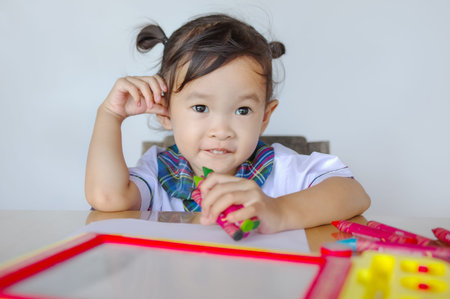 Happy cute asian little kid sitting at table and playing with colorful toy.の写真素材