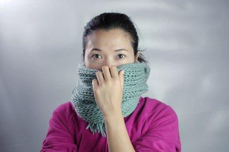 Woman wearing pink dress in winter clothing has scarf off her nose in the concept of healthy cold air.の写真素材