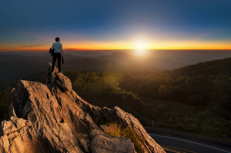 Concept vision, Young businessman wearing comfortable casual suit jacket standing holding business bag on top of peak mountain and looking forwards, success, competition and leader concept.の写真素材