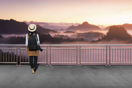 Asian female tourists, She wears casual style Japanese.with simple black backpack and camera with lens behind looking landscape view of autumn.の写真素材