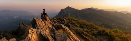 Panorama Mountain landscape with sunset on (Doi Pha Tang) viewpoint, Chiang Rai Thailand. Doi Pha Tang offers the best spot to watch the scenic Mekong river at the hilltop. Woman on top.の写真素材