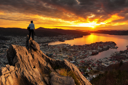 Concept vision, Young businessman wearing comfortable casual suit jacket standing holding business bag on top of peak mountain and looking forwards, success, competition and leader concept.の写真素材