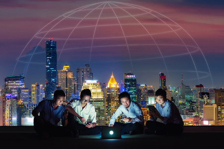 Asian business group in casual suits using smartphone, tablet and laptop for working or playing social networks and wep site on high-rise rooftop sites. Business and technology concept.の写真素材