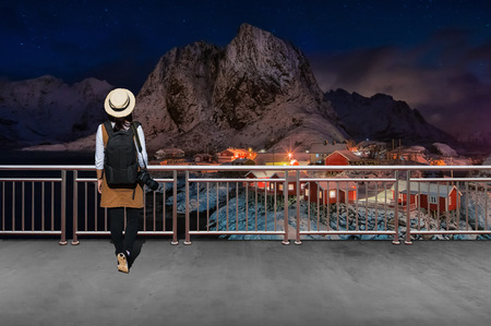 Asian female tourists, She wears casual style Japanese.with simple black backpack and camera with lens behind looking landscape view of winter in Norway.の写真素材