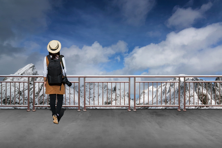 Asian female tourists, She wears casual style Japanese.with simple black backpack and camera with lens behind looking landscape view of winter in Norway.の写真素材
