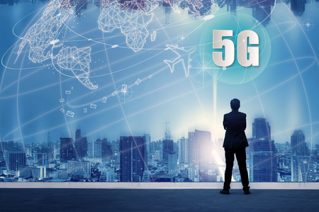 5G network wireless systems and internet of things with successful businessman standing on top of building and looking through Cityscape Skyline Night Light, Connect global wireless devices.の写真素材