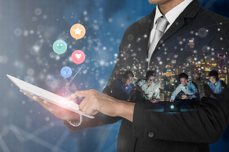 Double exposure of Businessman holding digital tablet, with smiley face, like, love and star emoticon on virtual touch screen. Customer service evaluation concept.の写真素材