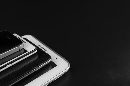 Stack of high-end smartphones on black desk.の写真素材