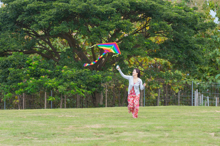 Women wearing red dress and happy with a kite on clear day.の写真素材