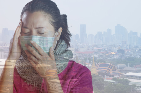 Asian women wear masks to prevent air pollution with background against "Toxic dust" covered the city of Bangkok has a health effect, Double exposure.の写真素材