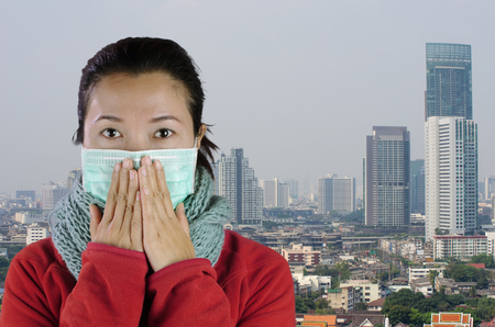 Asian women wear masks to prevent air pollution with background against "Toxic dust" covered the city of Bangkok has a health effect.の写真素材
